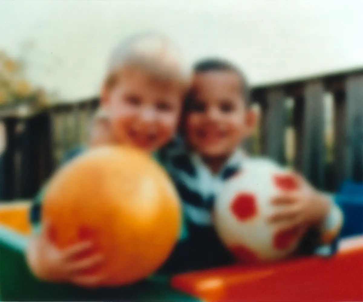 Two boys holding balls, seen through a hazy, dim, yellowed blur
