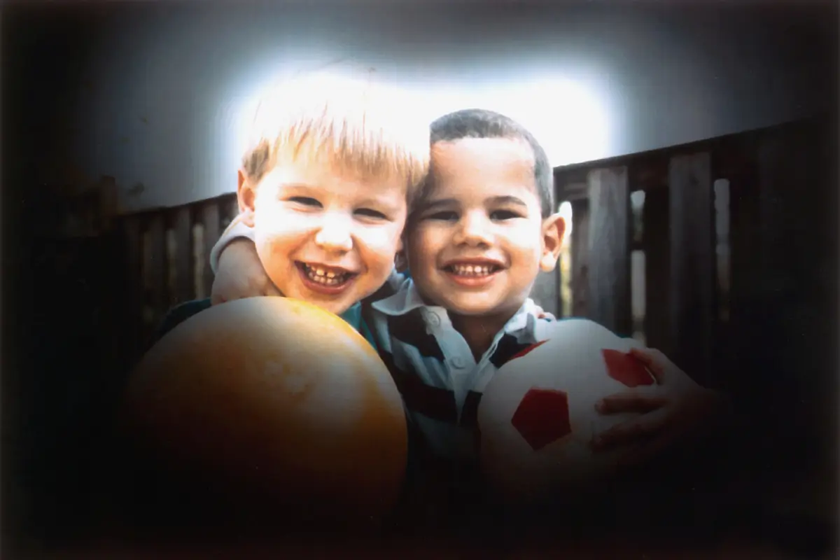 Two boys holding balls, with the edges of the scene dark and only the center clear