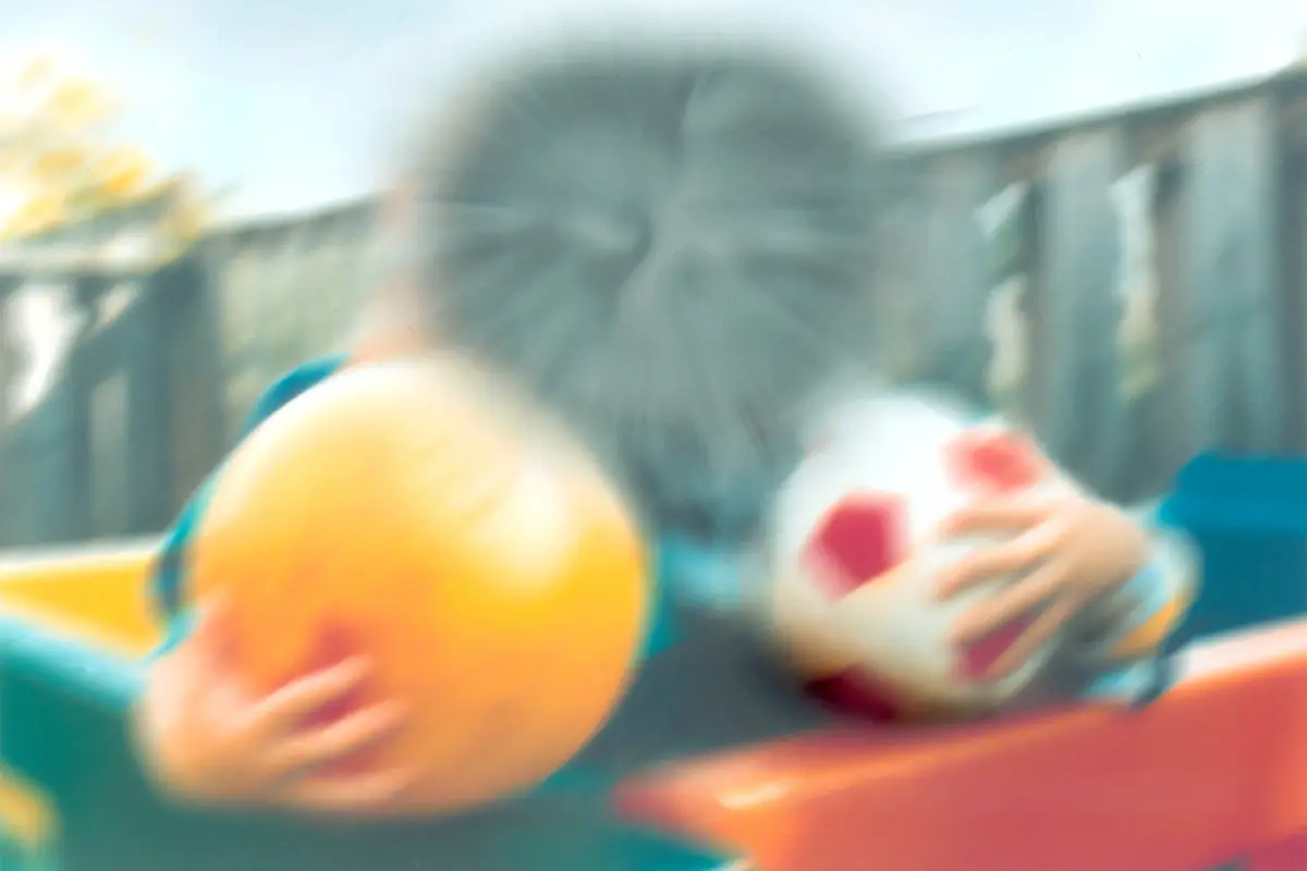 Two boys holding balls, with a blurred smudge hiding their faces in the middle of the view